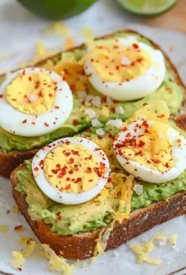 Avocado toast topped with a perfectly cooked egg on a plate.