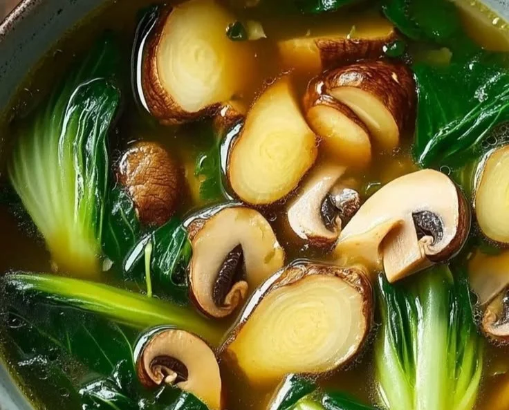 Bowl of savory Bok Choy Soup garnished with green onions and herbs