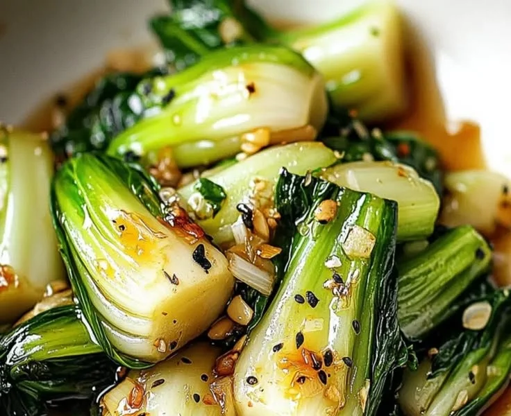 Image of sautéed bok choy garnished with garlic and sesame seeds.