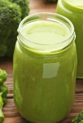 Freshly made broccoli juice in a glass with a green background