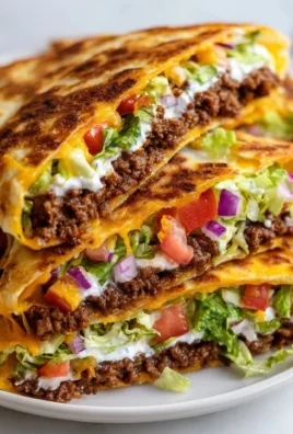 Two homemade beef crunchwraps cut in half with fresh ingredients on a plate.