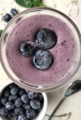 A colorful high fiber smoothie in a glass with fresh fruits and greens.