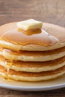 Fluffy buttermilk pancakes stacked on a plate with syrup and berries