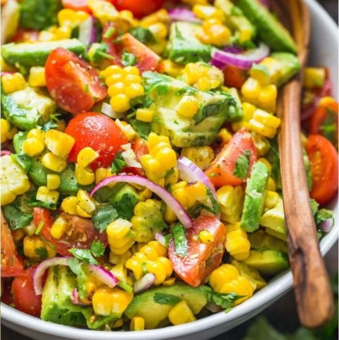 Bowl of fresh corn salad with colorful vegetables and dressing