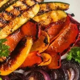 Plate of colorful grilled vegetables including bell peppers, zucchini, and eggplant.