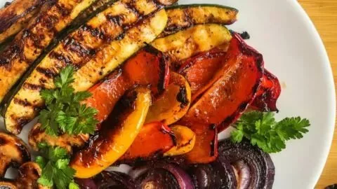 Plate of colorful grilled vegetables including bell peppers, zucchini, and eggplant.