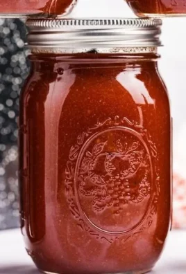 Bottle of homemade BBQ sauce with ingredients and grilling tools in the background