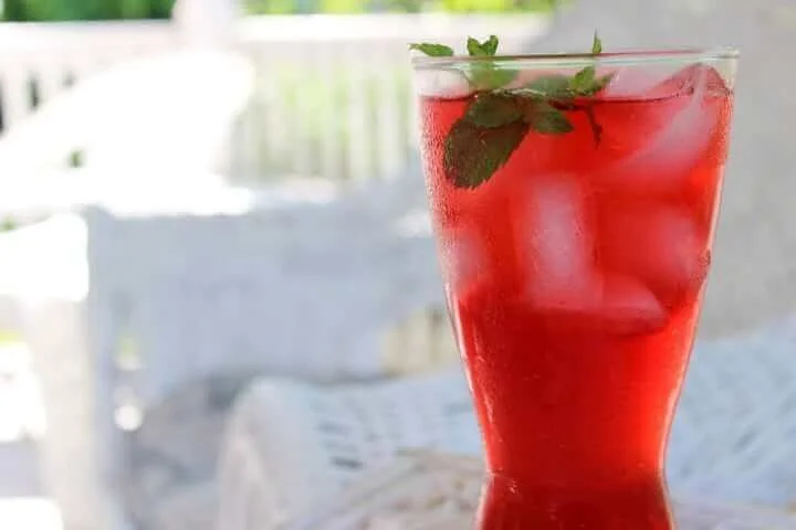 Homemade lacto-fermented raspberry soda in a glass with fresh raspberries