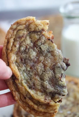 A batch of homemade pan-banging chocolate chip cookies on a cooling rack.