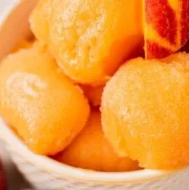 Delicious homemade Peach Sorbet served in a bowl with fresh peaches