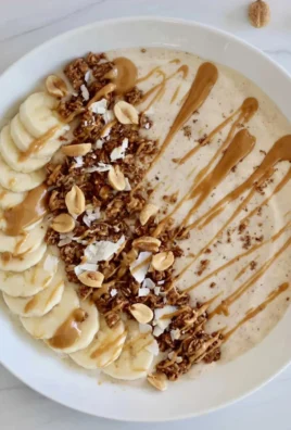 Delicious peanut butter smoothie bowl topped with fruits and granola.