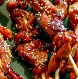 Sticky Bourbon Chicken Skewers with glaze and herbs on a grill