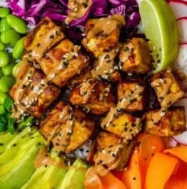 Delicious Tofu Buddha Bowl topped with homemade peanut sauce and fresh vegetables