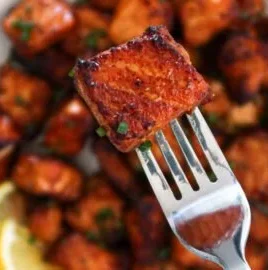 Crispy air fryer salmon bites served on a plate with herbs