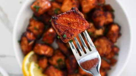 Crispy air fryer salmon bites served on a plate with herbs