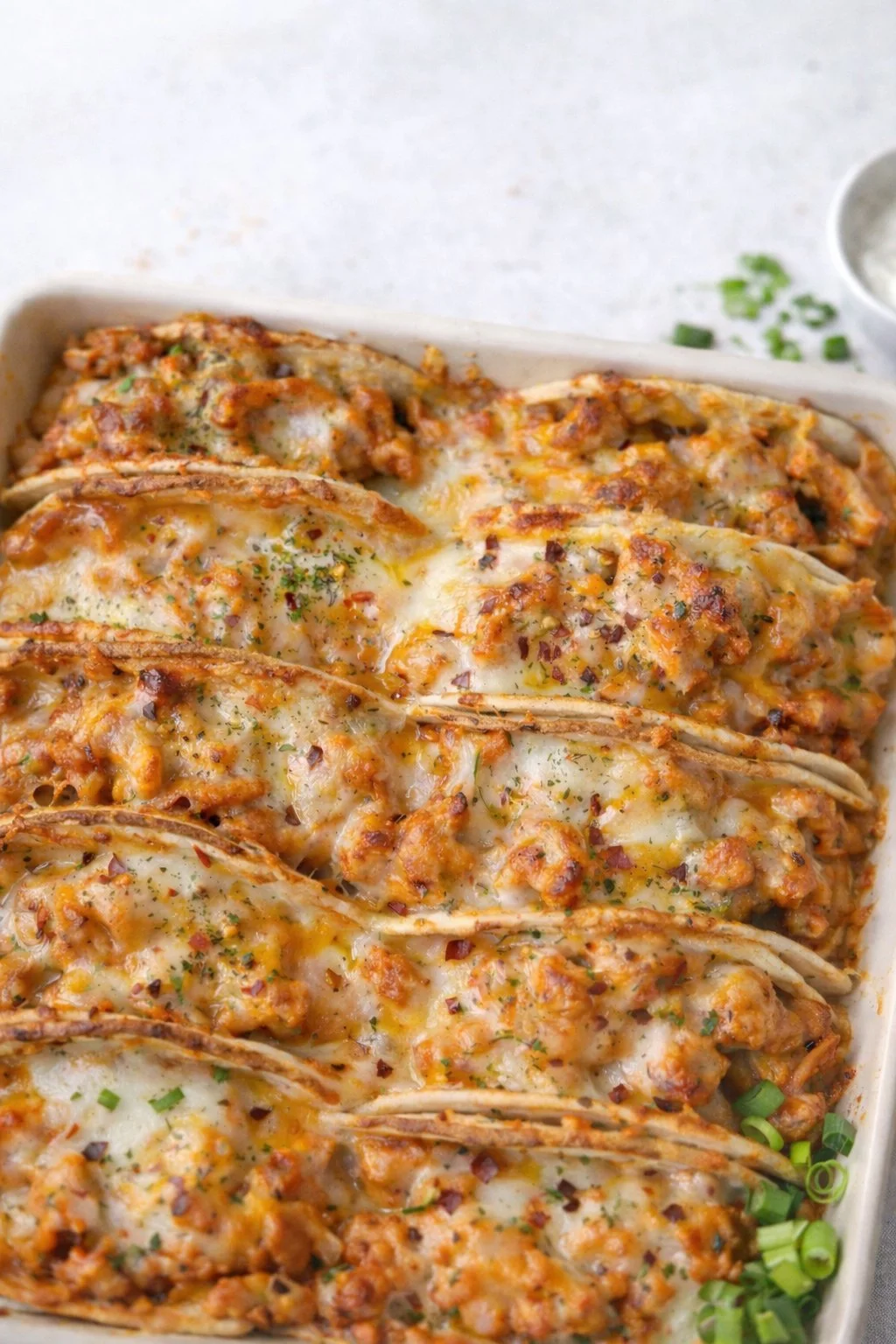 Baked chicken bacon ranch tacos topped with melted cheese and fresh ingredients.