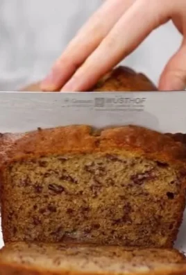 Homemade banana bread on a wooden table with ripe bananas