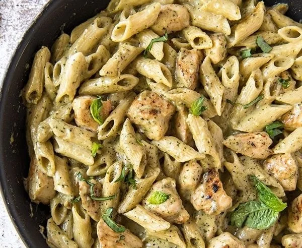 Creamy Cheesy Pesto Chicken Pasta garnished with fresh basil and cheese