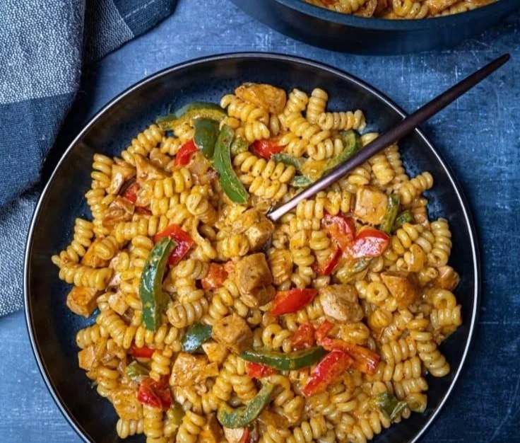 Delicious creamy chicken fajita pasta served in a bowl with colorful peppers.