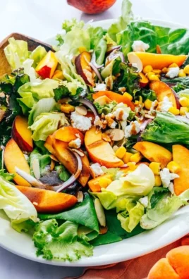 A vibrant fresh peach salad with greens and colorful ingredients
