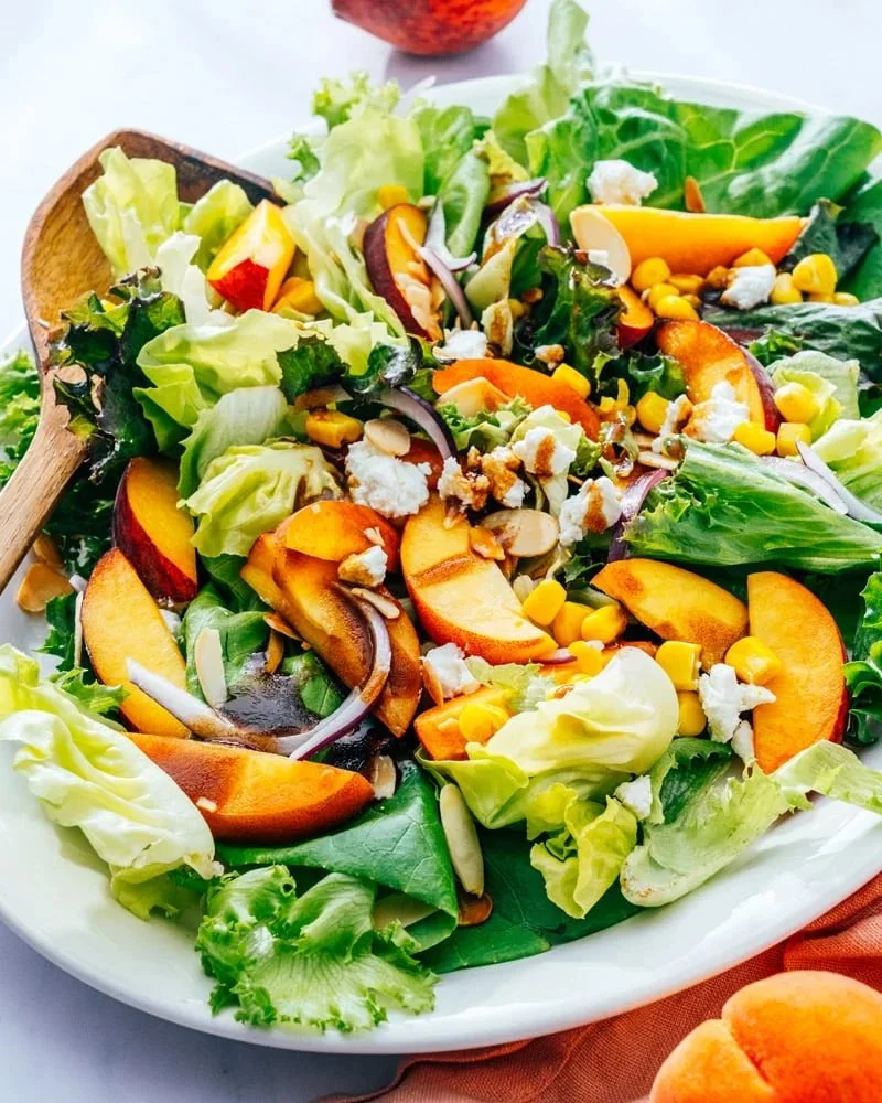A vibrant fresh peach salad with greens and colorful ingredients