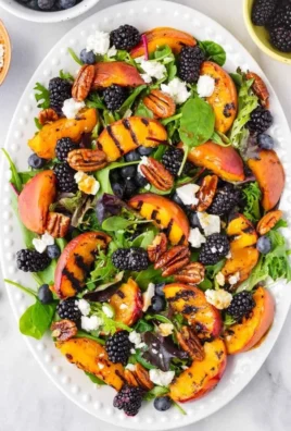 Colorful grilled peach salad with mixed greens, feta cheese, and nuts