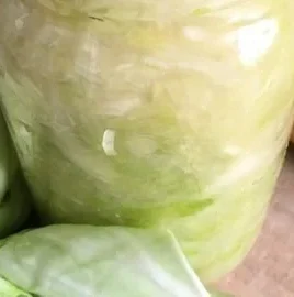 Homemade sauerkraut in a glass jar on a wooden table