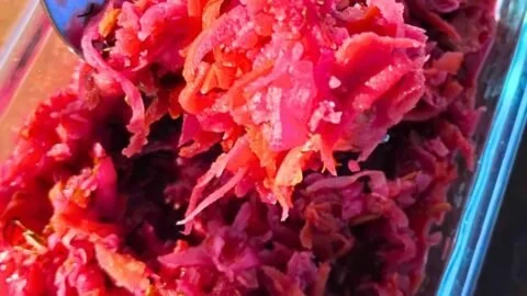 Bowl of homemade fermented coleslaw with root vegetables on a wooden table