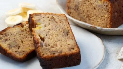 A slice of indulgent olive oil banana bread with a golden crust and chocolate chips
