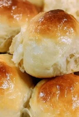 Homemade Sourdough Hawaiian Rolls topped with sesame seeds on a wooden board