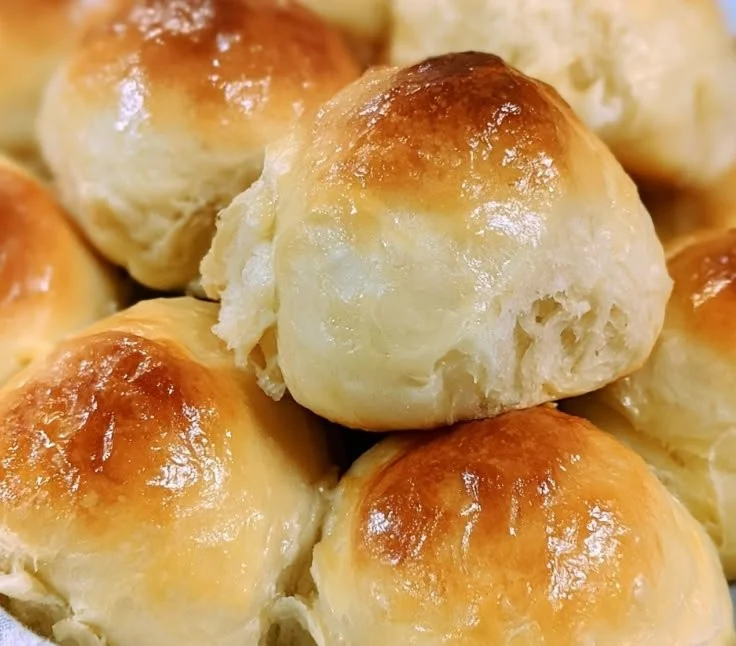 Homemade Sourdough Hawaiian Rolls topped with sesame seeds on a wooden board