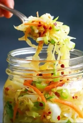A jar of homemade fermented cabbage with colorful spices and herbs