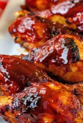 Baked BBQ chicken drumsticks with a sticky glaze, served on a white plate.