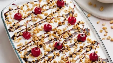 Deliciously layered Banana Split Cake topped with whipped cream and cherries