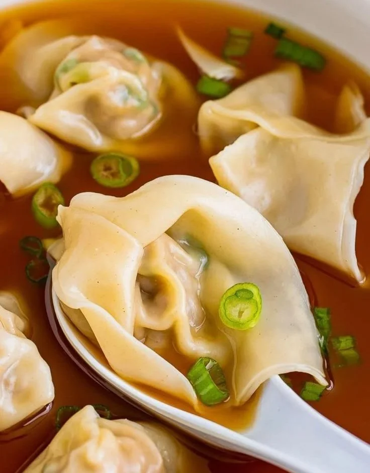Delicious bowl of wonton soup with fresh ingredients and herbs