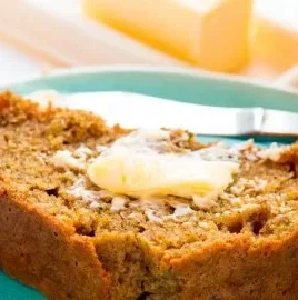 Slice of moist orange zucchini bread with orange zest garnish