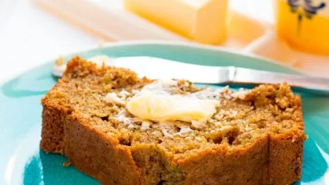 Slice of moist orange zucchini bread with orange zest garnish