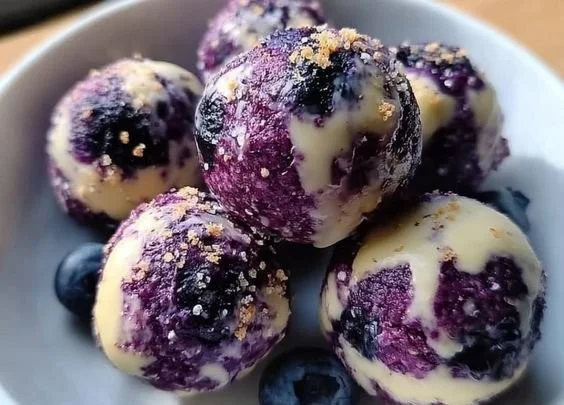 Blueberry cheesecake bites topped with fresh blueberries on a white plate