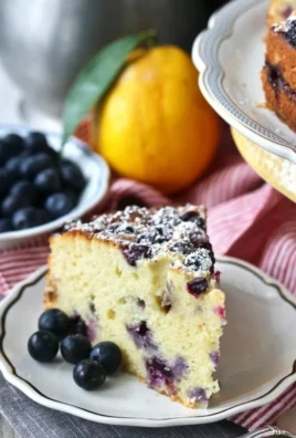 Blueberry lemon ricotta tea cake served on a plate with fresh blueberries.