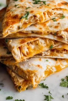 Plate of cheesy Chicken Quesadillas with grilled chicken and fresh toppings