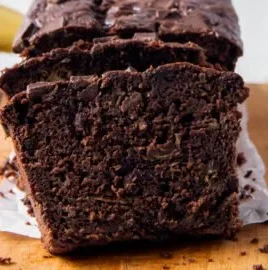 Slice of chocolate zucchini banana bread topped with chocolate chips on a plate