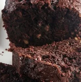 Loaf of chocolate zucchini bread with a slice cut out, showcasing its moist texture.