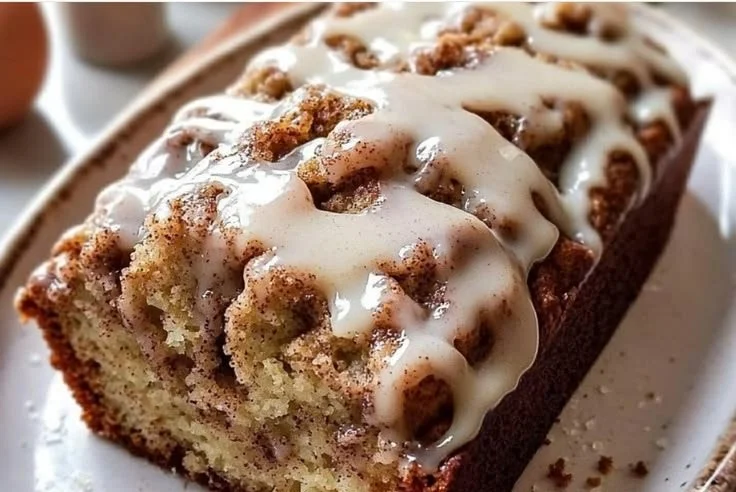 Slice of cinnamon roll banana bread topped with cream cheese icing