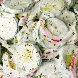 Creamy cucumber salad served in a bowl with fresh herbs and spices