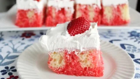 Delicious Easy Strawberry Poke Cake topped with fresh strawberries and cream