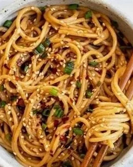 Delicious bowl of Garlic Sesame Noodles topped with sesame seeds and green onions.