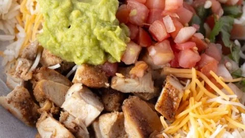 Grilled Chicken Burrito Bowl with rice and beans garnished with fresh ingredients