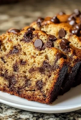 Moist chocolate chip banana bread loaf with chocolate chips on a wooden table