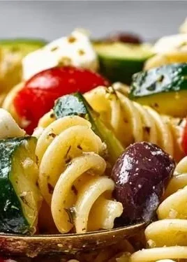 A colorful bowl of Italian pasta salad with fresh vegetables and dressing.