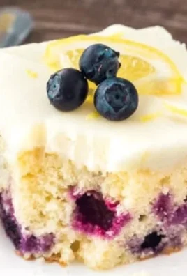 Lemon blueberry cake with fresh blueberries and lemon zest on a white plate